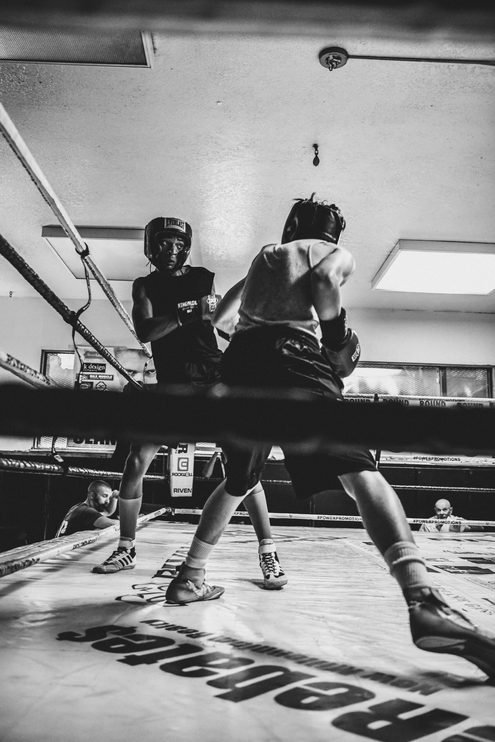 Intense black and white shot of two boxers sparring in a gym.